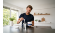Man mengt elektrolytenpoeder in een glas water in een lichte keuken als voorbereiding op hydratatie en sportherstel.